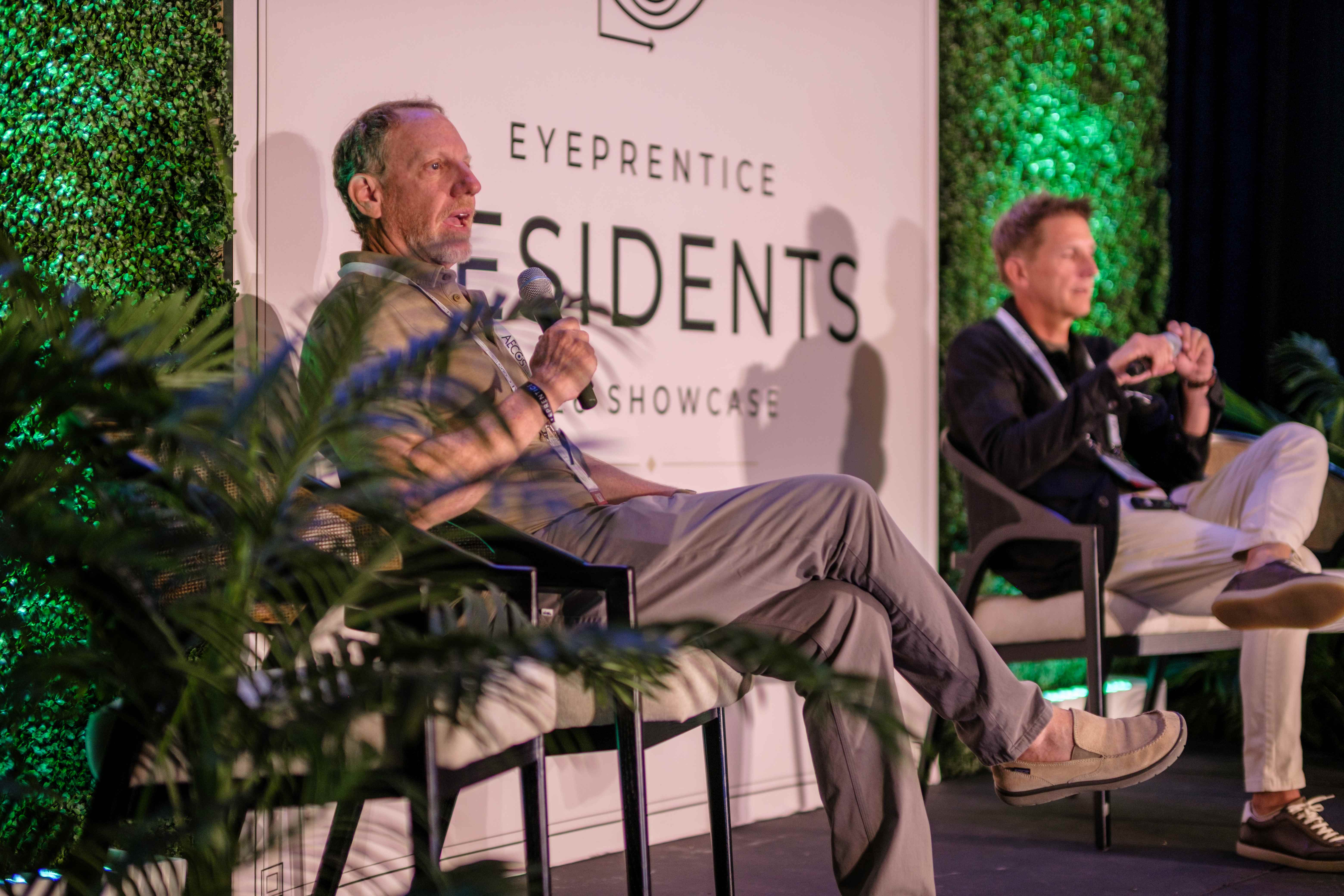 Two faculty members in a seated fireside chat on stage