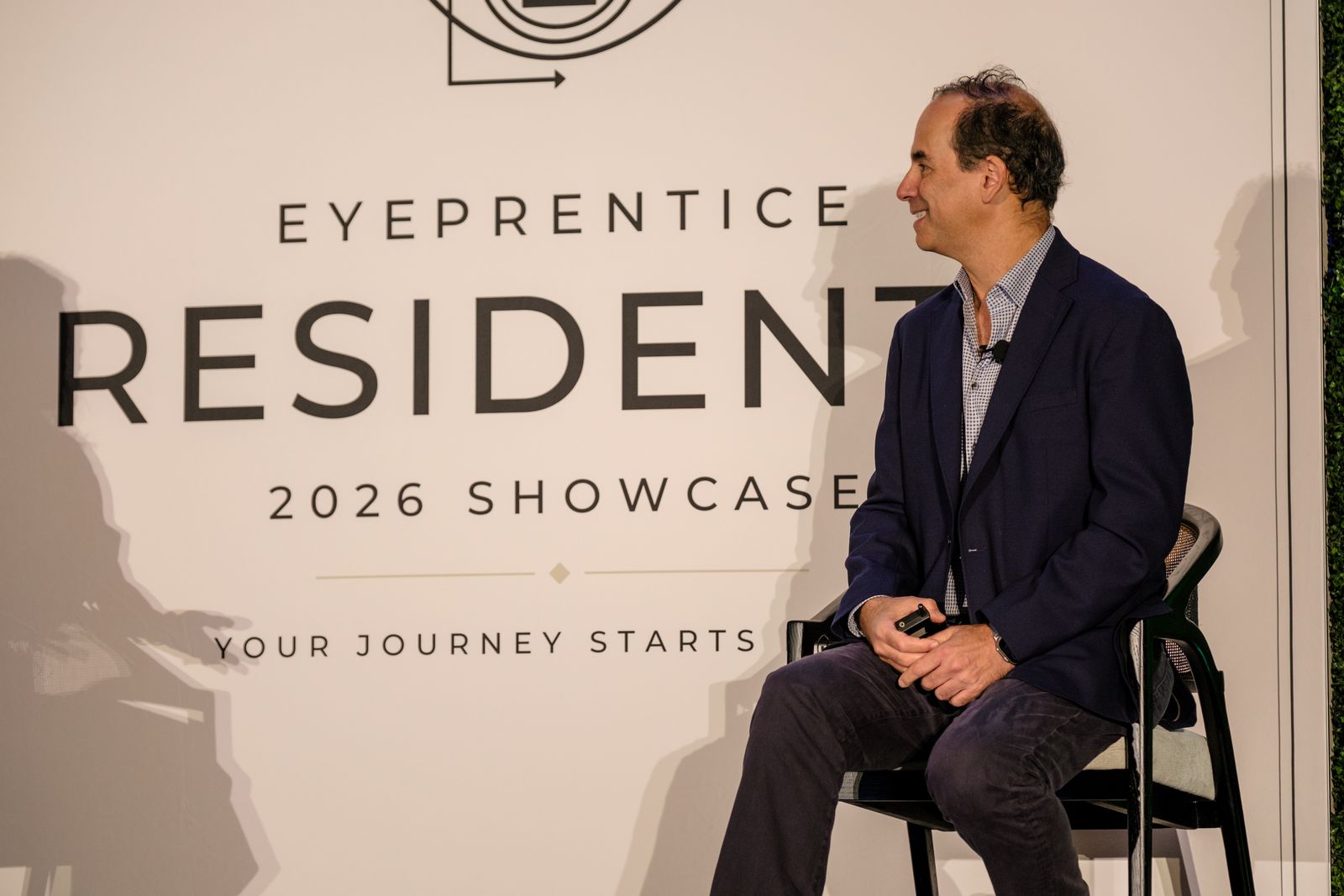 A speaker seated in front of the Eyeprentice 2026 Showcase backdrop