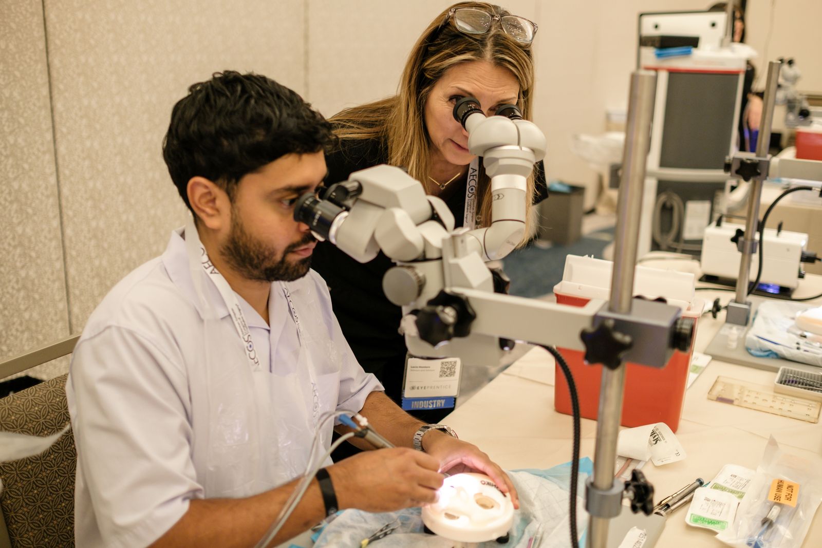 An instructor guiding a resident through practice at the microscope
