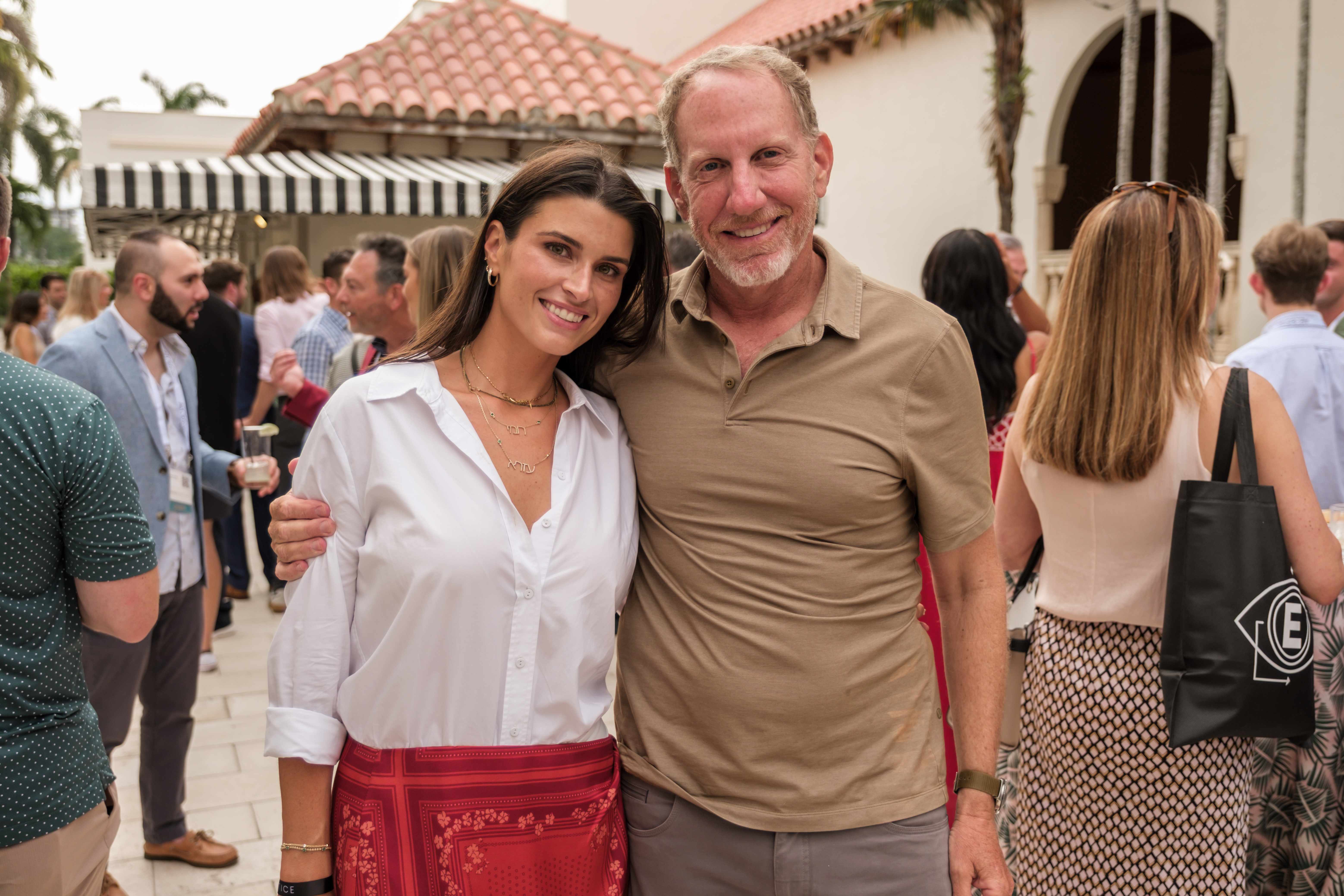 Two attendees posing together at an outdoor courtyard reception